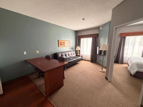 a living room with a couch and a bed and a desk at River Hills Hotel- Mankato in Mankato