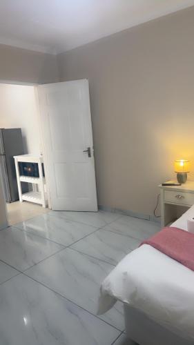 a white room with a bed and a white door at Tesco Accommodation in Gqeberha