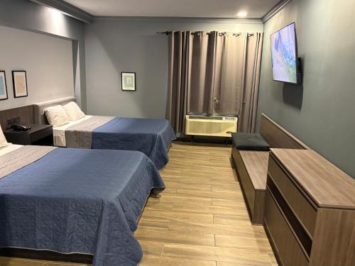 a hotel room with two beds and a flat screen tv at Hotel Le-Gar in Monterrey