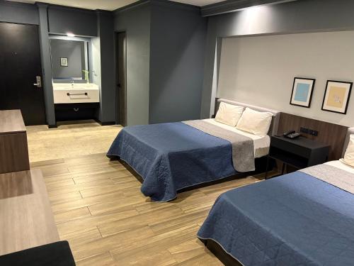 a hotel room with two beds and a bathroom at Hotel Le-Gar in Monterrey