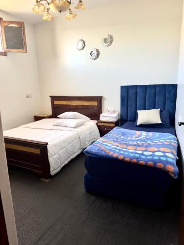 a bedroom with two beds and a blue headboard at Appartement confort et sérénité in Ikhorbane