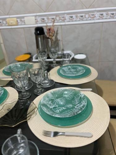 a table with green plates and glasses on it at Casa AGV 77 - Gaibu Beach in Cabo de Santo Agostinho