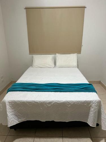 a white bed with blue sheets and pillows at Casa AGV 77 - Gaibu Beach in Cabo de Santo Agostinho