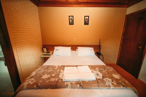 a bedroom with a bed with two towels on it at Hotel Geneve - 2km do Capivari in Campos do Jordão
