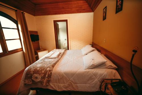 a bedroom with a bed in a room with a window at Hotel Geneve - 2km do Capivari in Campos do Jordão