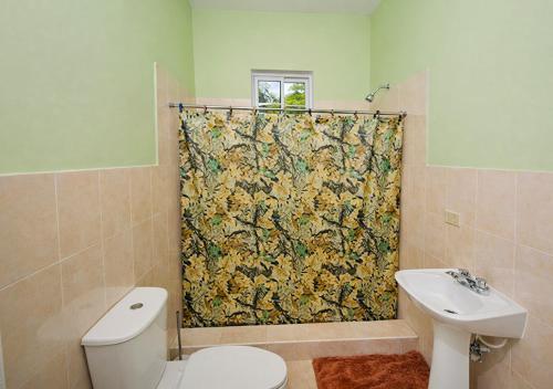 a bathroom with a shower curtain with a toilet and sink at Scarlett Near Cane River Falls in Bull Bay