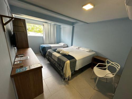 a bedroom with two beds and a table and a window at Pousada Encantos do Mar in Barra de Camaratuba