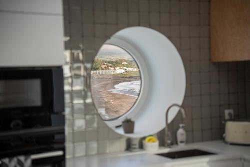 a mirror over a sink with a view of a beach at The Lookout | Private Beach Access in São Roque