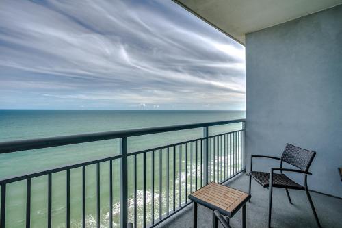 a balcony with two chairs and a table and the ocean at Oceanfront Luxury King Suite at Oceans One Resort in Myrtle Beach