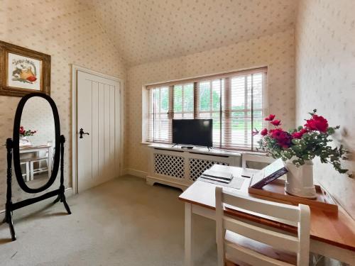 a room with a desk and a television and a table with flowers at Cottage 1 - Uk46611 in Broughton