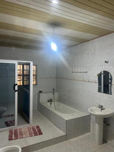 a bathroom with a bath tub and a sink at Macdel Guesthouse And Condos in Kumasi
