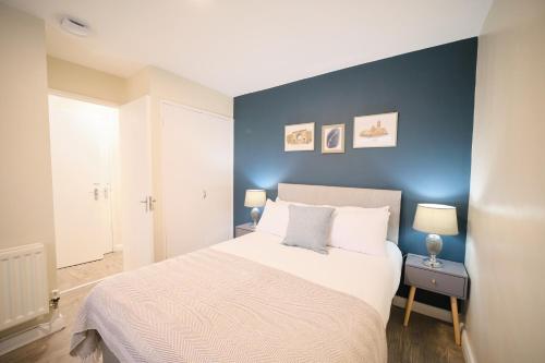 a bedroom with a bed with a blue accent wall at 1 Bedroom Apartment By Travel Lets Holiday Homes Derry Beside The City Walls in Derry Londonderry