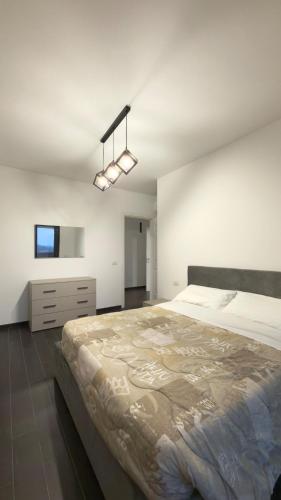 a white bedroom with a large bed and a chandelier at Urban Nest Living in Sesto San Giovanni