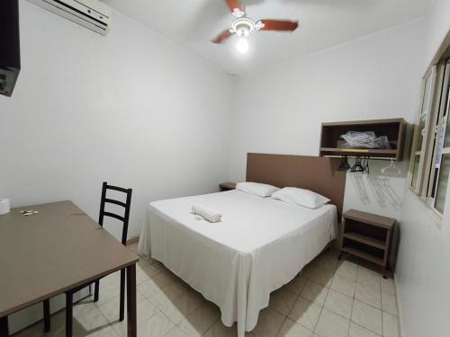a bedroom with a bed and a table and a ceiling fan at Hotel Mirian in Patos de Minas