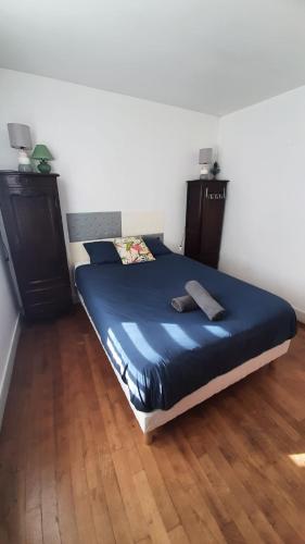 a bedroom with a bed with blue sheets and wooden floors at Maison avec cour et jardin in Marolles-sur-Seine