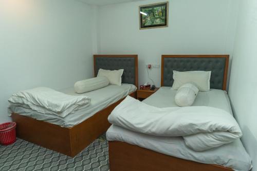 two twin beds in a room with at Hotel Tawhid in Rangpur