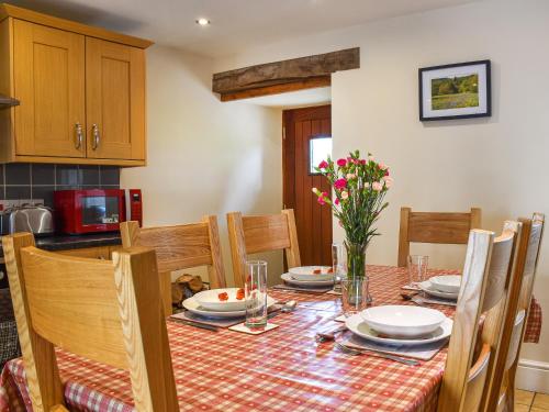 a dining room table with chairs and a tablecloth on it at Llandremor Fawr Cottage - Cc in Llanedy