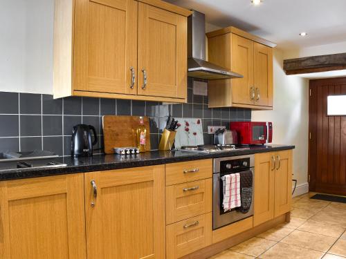 a kitchen with wooden cabinets and a stove top oven at Llandremor Fawr Cottage - Cc in Llanedy