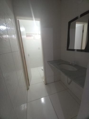 a white bathroom with a sink and a mirror at Casa Samambaia in Piranhas