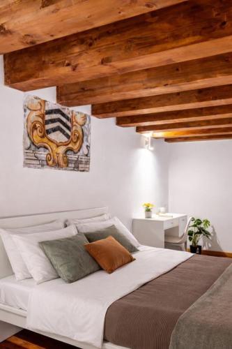 a bedroom with a large white bed with wooden ceilings at Open Sicily Homes - Near the Central Train Station in Palermo