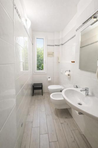 ein weißes Badezimmer mit zwei Waschbecken und zwei Toiletten. in der Unterkunft Hotel Sasselli Dipendenza Hotel Zamagna in Cesenatico