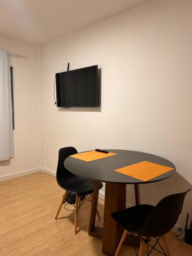 a table with two chairs and a tv on a wall at Apartamento Loft in Balneário Camboriú