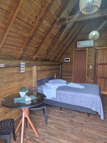 a bedroom with a bed and a table in a room at Cabanas das Oliveiras in Torres