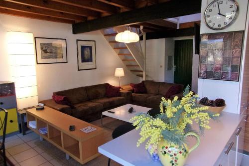 a living room with a couch and a clock on the wall at Beautiful 67 m duplex with gardengolf view in Moliets-et-Maa