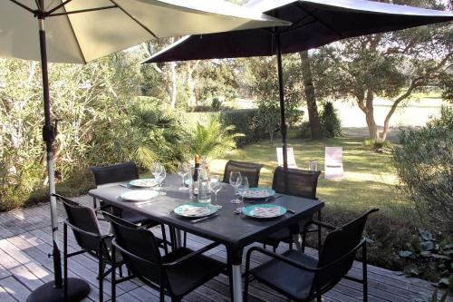 a black table and chairs under an umbrella at Beautiful 67 m duplex with gardengolf view in Moliets-et-Maa