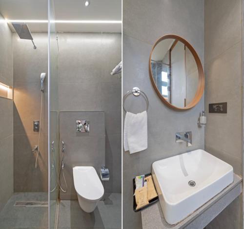 a bathroom with a sink and a toilet and a mirror at The Kalvin Plaza in New Delhi