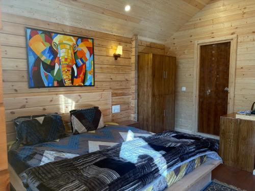 a bedroom with a bed with a painting on the wall at Samlaun Chalet and Retreat in Kanatal
