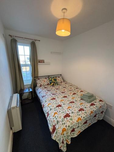 a bedroom with a bed with a floral bedspread and a window at Leamington Spa Boutique Two Bedroom Flat in Leamington Spa