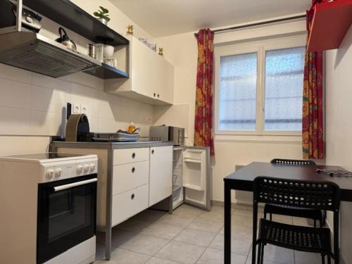 una cocina con estufa y una mesa con sillas en LE ROUGET, en Beaucaire