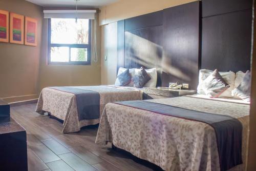 ein Hotelzimmer mit zwei Betten und einem Fenster in der Unterkunft Hotel Las Iglesias, Cholula in Cholula de Rivadavia