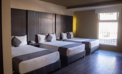 ein Hotelzimmer mit zwei Betten und einem Fenster in der Unterkunft Hotel Las Iglesias, Cholula in Cholula de Rivadavia