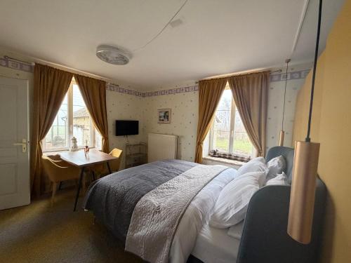 a bedroom with a bed and a desk and windows at Bed & Breakfast Chateau Saintonge in Le Chevain