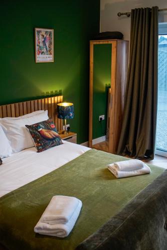 a green bedroom with a bed with two towels on it at Cloudhowe Cottage Ensuite Rooms & Studio Inverness in Inverness