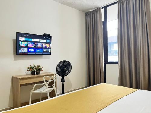 a hotel room with a bed and a desk and a tv at HOTEL CATALUÑA PEREIRa in Pereira