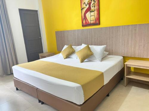 a bedroom with a large bed with yellow walls at HOTEL CATALUÑA PEREIRa in Pereira