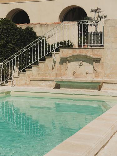 a swimming pool with a staircase next to a building at Maison Bérard Hôtel - Restaurant - Spa in La Cadière-dʼAzur