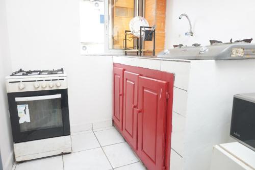 kuchnia z kuchenką i czerwonymi drzwiami w obiekcie Complexe A8CLOS w mieście Duala