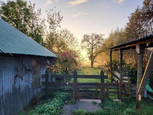 a wooden fence next to a building and a field at B&B Koe en Kussen in Bodegraven