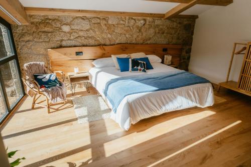 a bedroom with a large bed and a stone wall at iSlow Costa da Morte in Laxe