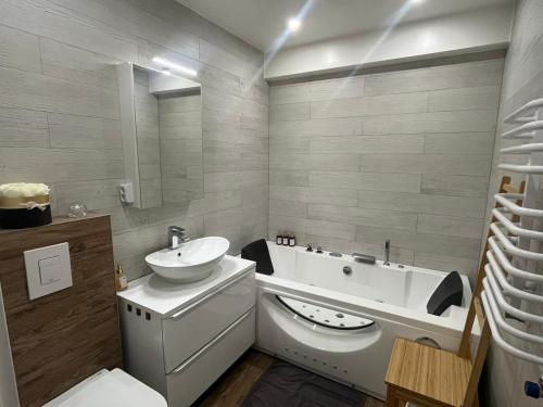 a bathroom with a sink and a tub and a toilet at Apartament w Centrum z wanną z hydromasażem in Kętrzyn