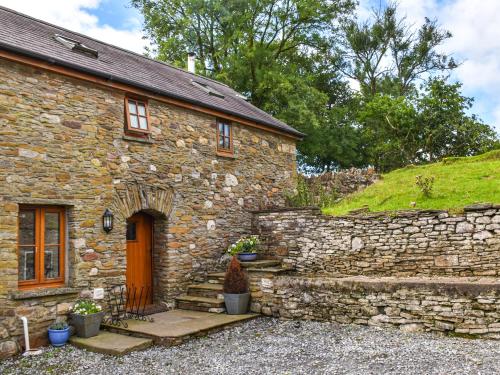 a stone house with a stone wall and a door at Llandremor Fawr Cottage - Cc in Llanedy