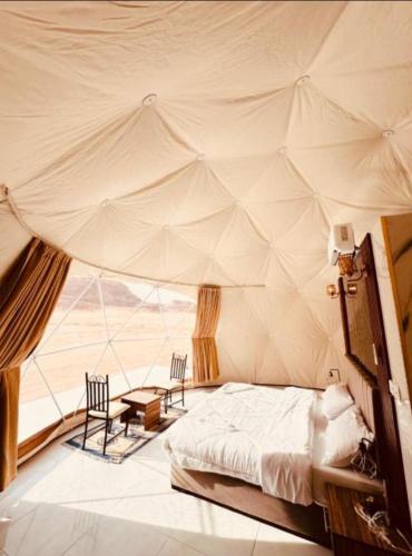 a bedroom with a tent with two chairs and a bed at RUM iSLAND bubble LUXURU CAMP in Wadi Rum