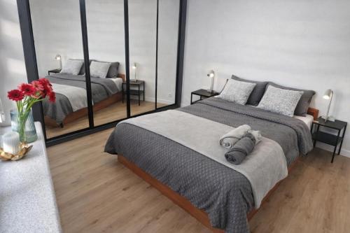 a bedroom with two beds and a vase with red flowers at Apartament w Centrum z wanną z hydromasażem in Kętrzyn
