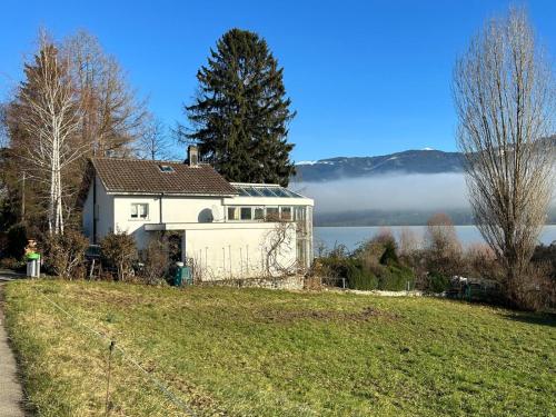 a white house on a hill next to a lake at Rose Garden Switzerland in Avry devant Pont