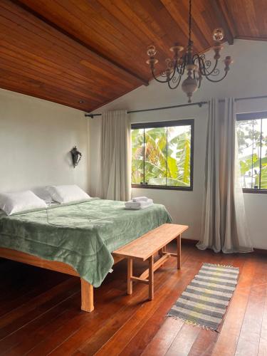 a bedroom with a bed and a bench and windows at Chalé da Mata Lavras Novas in Lavras Novas