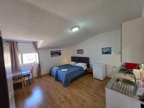 a bedroom with a bed and a kitchen with a sink at Tonino Apartment in Pag